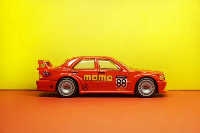 Diecast touring merah dengan livery MOMO dan latar kuning